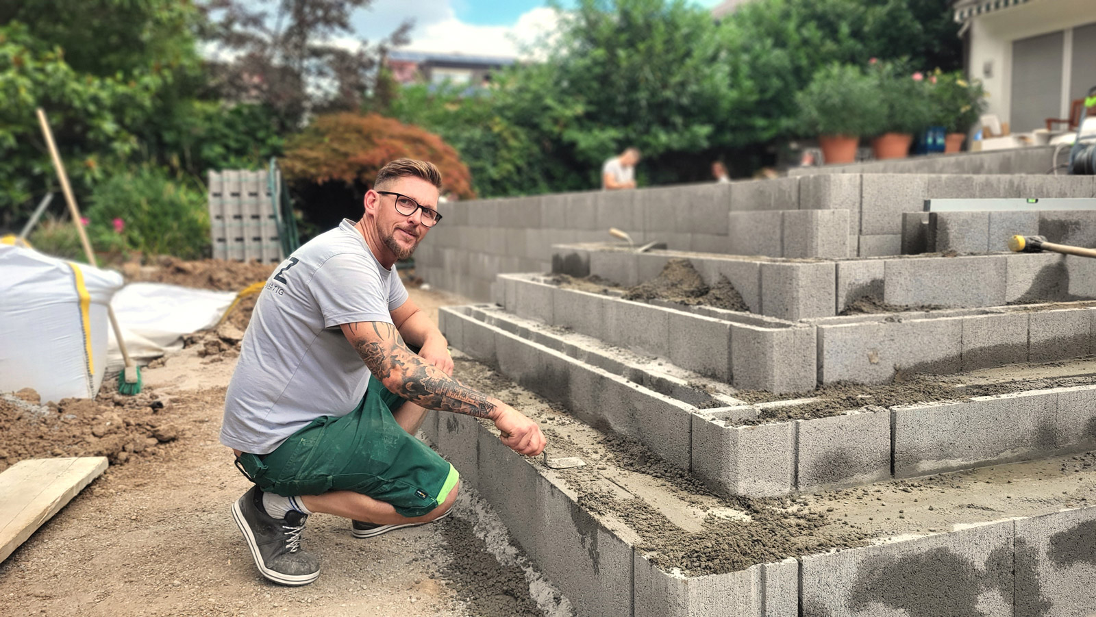 Einer unserer Mitarbeiter errichtet eine Natursteinmauer in einem Garten.