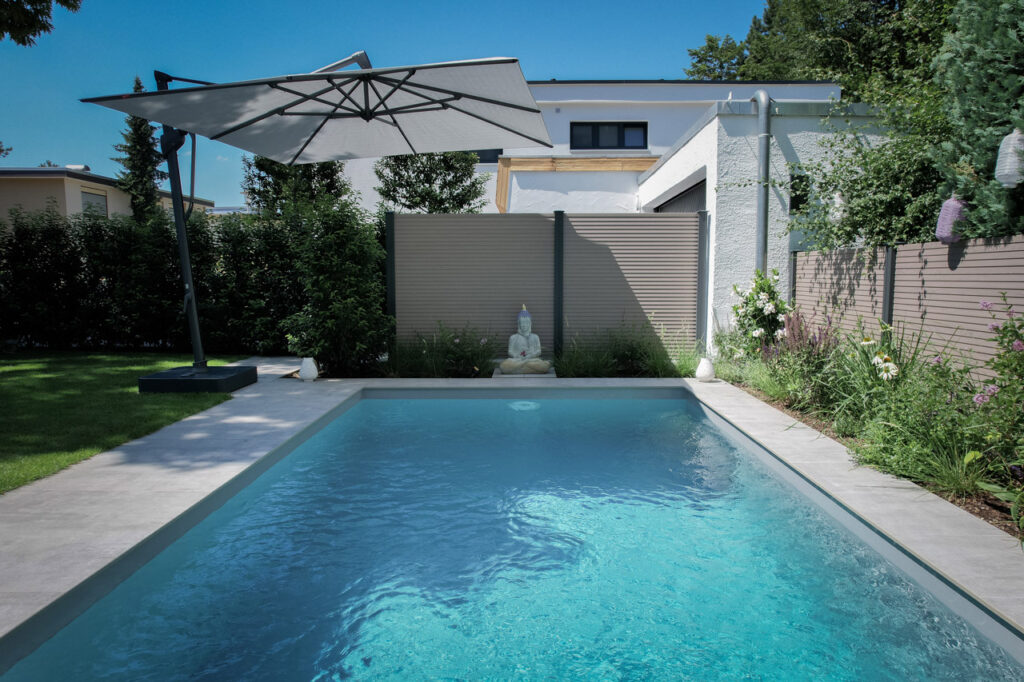 Garten mit Pool - eingerahmt von Sichtschutz aus Hecken und Zaunelementen.