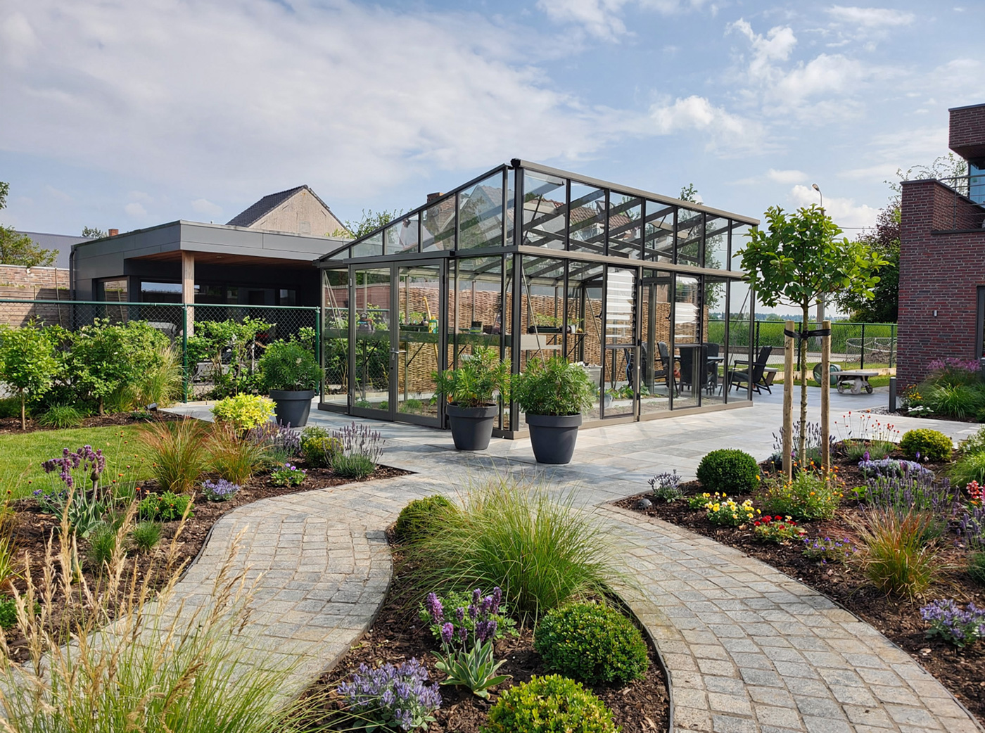 Ein Gewächshaus in moderner Architektur steht im blühenden Garten
